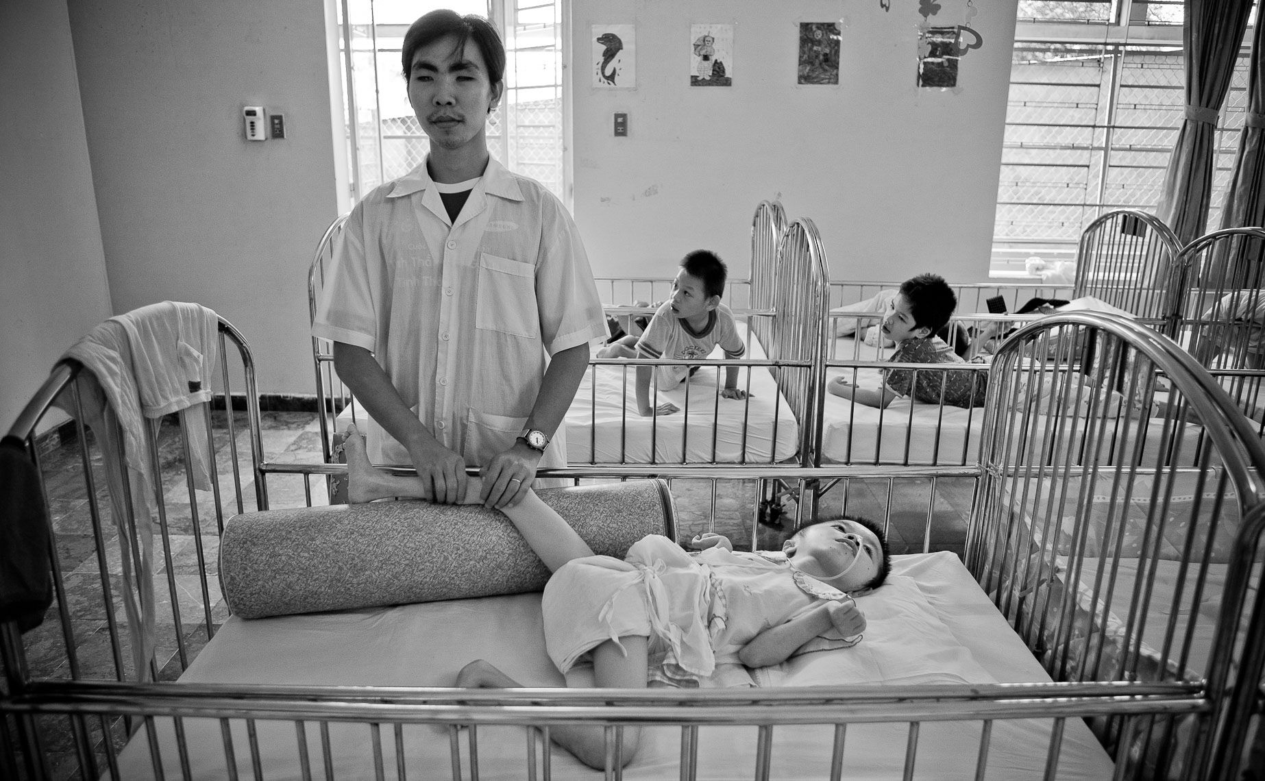 young handicapped orphan boy receives massage from blind nurse in a vietnamese orphanage - ho chi minh vietnam