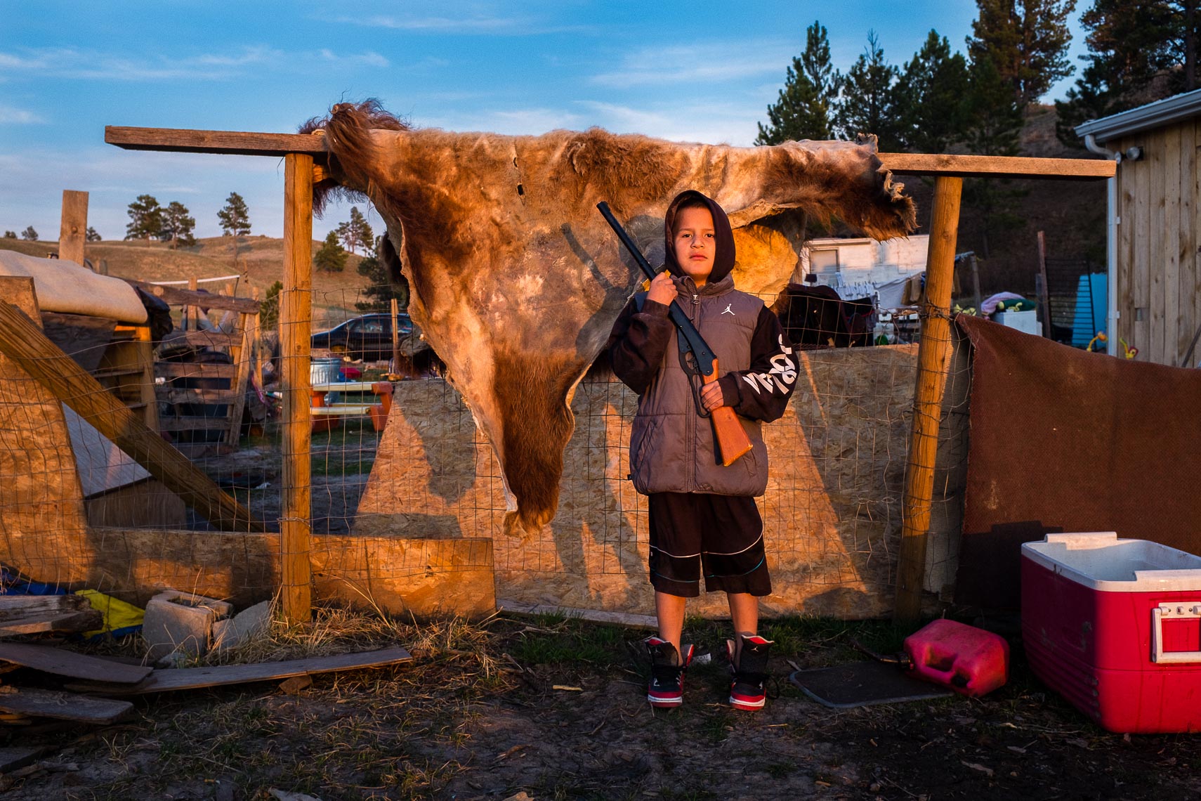 Oglala Sioux nation boy stands with his pellet gun in front of a bison buffalo hide on the pine ridge indian reservation 