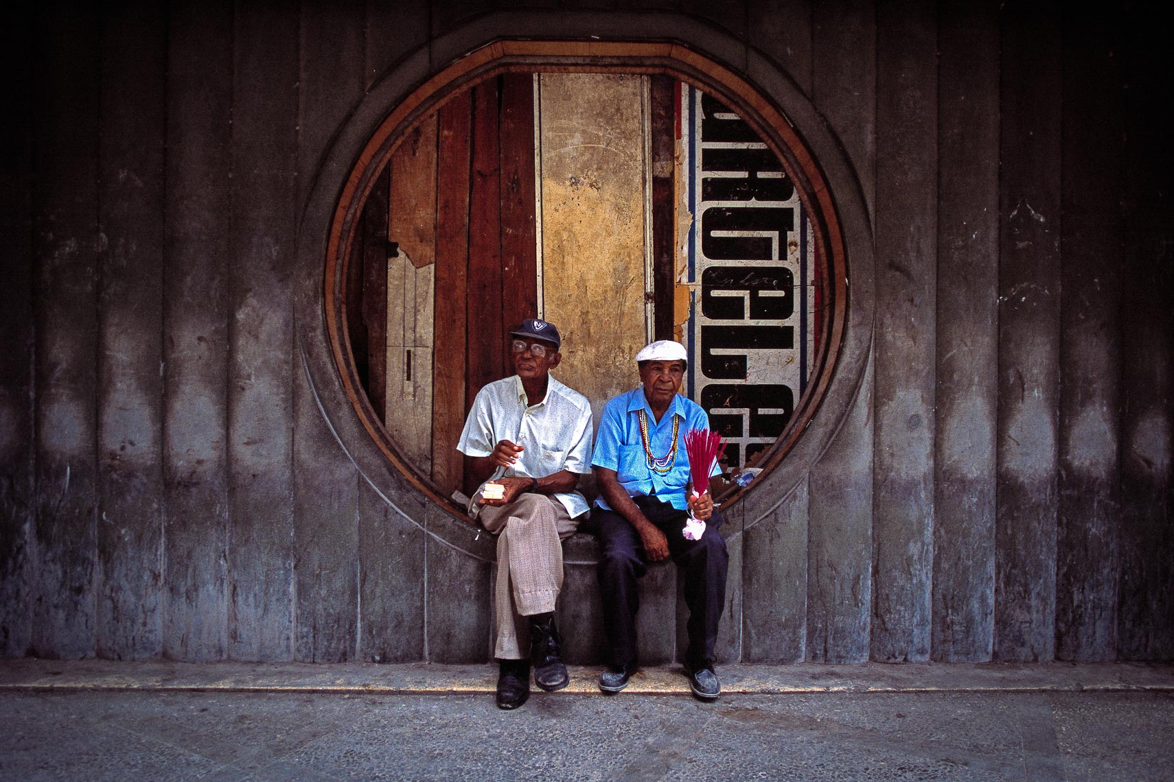 two old men in hats sit on street in havana cuba