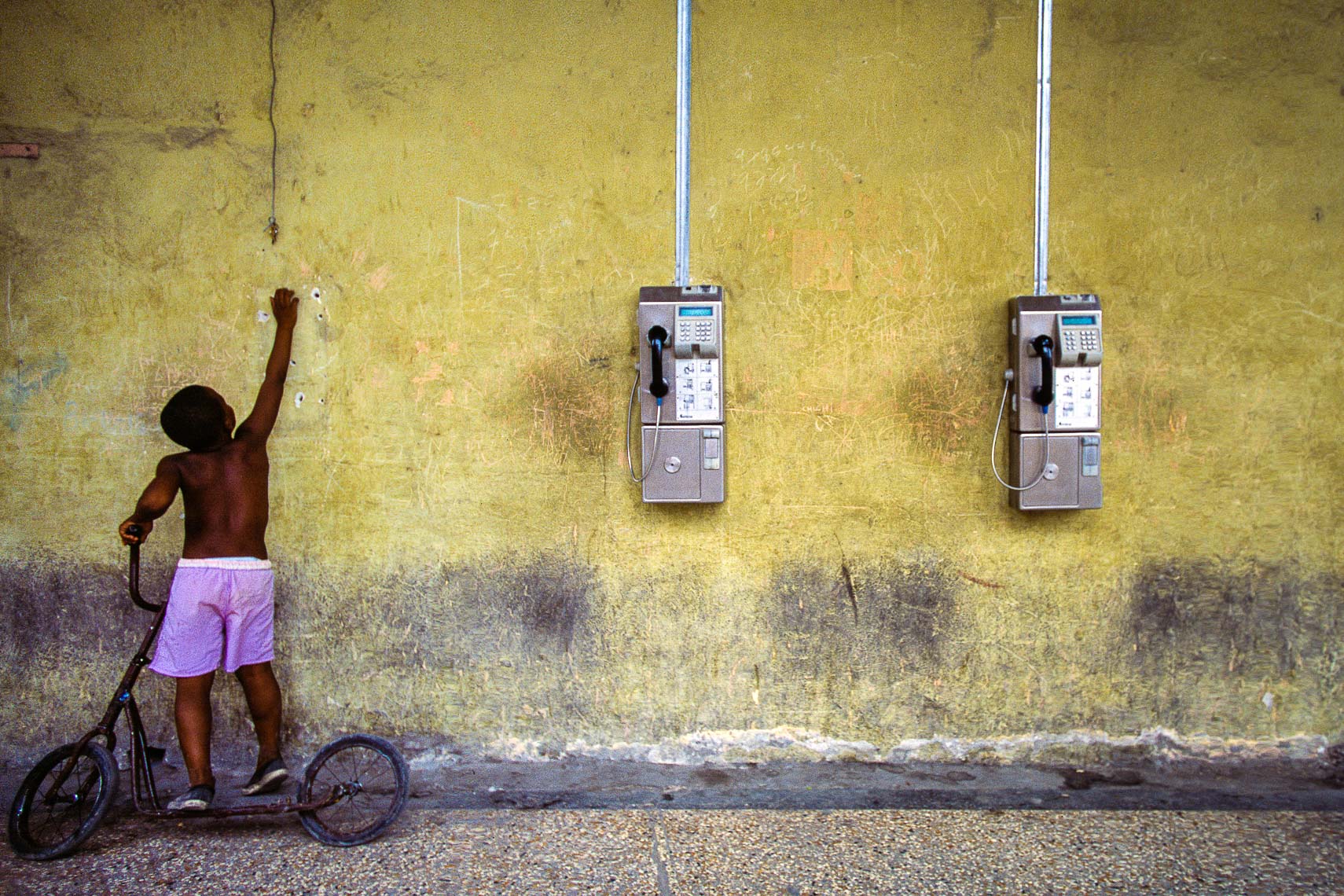 boy reaches for old pay phone in havana cuba