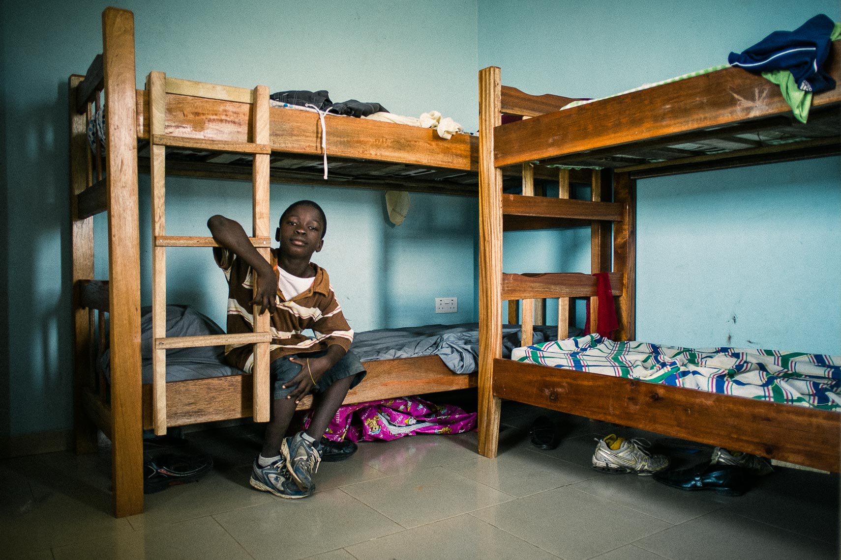 orphan boy sits on his bed at the city of refuge orphanage in tema ghana