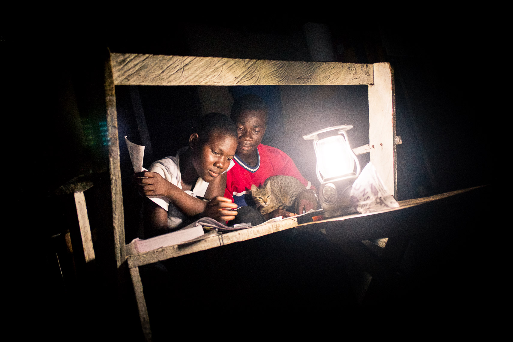 school teacher tutors student at home with lamp light - teshie nungua