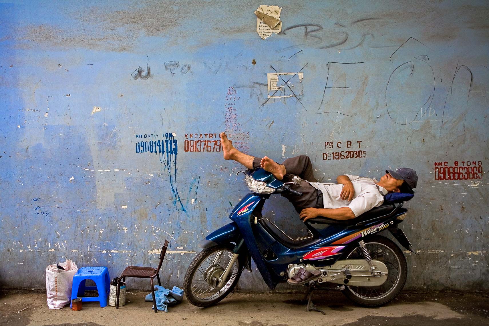 man naps sleeps on motorcycle in alley ho chi minh city vietnam